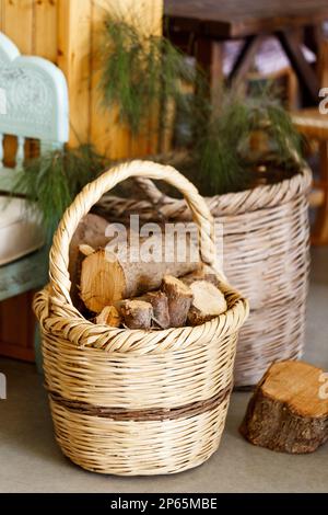 Panier en osier avec bois coupé sur le sol blanc à l'intérieur. Banque D'Images