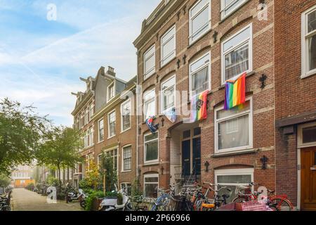 quelques vélos garés sur le côté d'une rue devant une rangée de bâtiments avec des drapeaux suspendus des fenêtres Banque D'Images