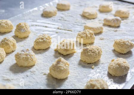 Le plat syrniki d'Ukrianian est cuit dans une cuisine commerciale. Processus de cuisson des gâteaux au fromage blanc brut Banque D'Images