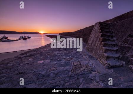 Lever du soleil au mur du port connu sous le nom de Cobb à Lyme Regis, Dorset, Angleterre, Royaume-Uni, Europe Banque D'Images