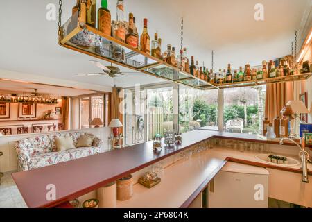 une cuisine avec beaucoup de bouteilles de vin sur les étagères au-dessus et une fenêtre ouverte dans la chambre à l'extérieur Banque D'Images