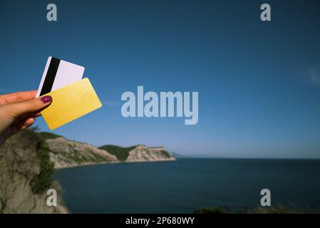 Carte d'or et de blanc en femme main sur le fond de la vue panoramique d'Arkoudilas point de vue, montagnes, Mer Ionienne Corfou, Grèce. Le concept de Banque D'Images