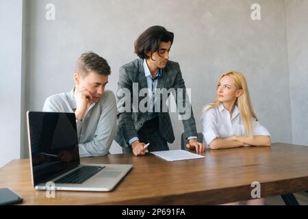 Portrait d'un avocat, d'un agent immobilier ou d'un conseiller financier parlant avec un jeune couple en remerciant pour son avis. Vue de face d'un courtier d'assurance ou d'un employé de banque Banque D'Images