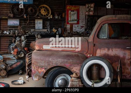 Ancien atelier de mécanicien de voitures abandonnées sur la route du désert. À l'intérieur se trouve un vieux pick-up F-1 de Ford. Banque D'Images