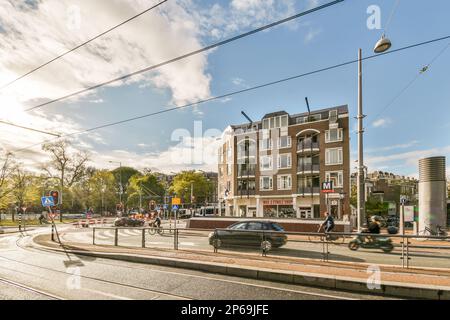 une rue de la ville avec des voitures et des personnes marchant sur le trottoir devant un immeuble d'appartements qui est entouré de lignes électriques Banque D'Images