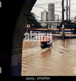 Un pilote colombien de livraison de nourriture de moto traverse un éclair de rue inondé par une tempête de pluie lourde pendant la saison des pluies annuelle à Cartagena, Colombie. Banque D'Images