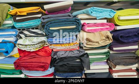 Des bobines de tissu se trouvent sur les tablettes du magasin. Piles de tissus de différentes couleurs Banque D'Images