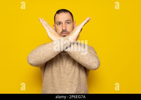 Non, absolument pas. Portrait de l'homme hispanique barbu en turtleneck montrant x signe avec des mains croisées signifiant stop c'est la fin Isolé sur Banque D'Images