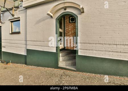 un bâtiment en brique qui a été peint vert et blanc avec une fenêtre voûtée en haut, en face de lui Banque D'Images