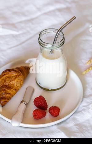 petit déjeuner français sur un lit, croissant, lait et baies fraîches, espace de photocopie Banque D'Images