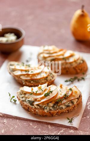 roquefort de fromage français et de tranches de pêches toasts sur une assiette carrée, sur une table sous des fleurs mimosa Banque D'Images