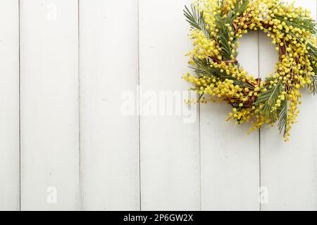 Belle couronne de fleurs mimosa jaunes sur fond de planches en bois blanc, espace de copie Banque D'Images