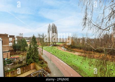 une zone extérieure avec des arbres et des maisons dans la distance, pris d'une fenêtre regardant vers le bas d'un chemin qui mène à un Banque D'Images