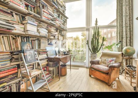 une salle de séjour avec beaucoup de livres sur les étagères, et une chaise dans le siège de fenêtre avant - oeil Banque D'Images