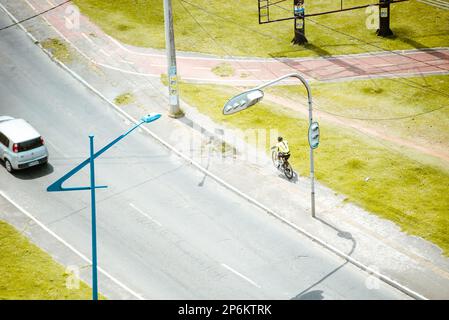 Salvador, Bahia, Brésil - 24 septembre 2022: Cycliste passant par la voie de voiture dans le quartier de Pernambues à Salvador, Bahia. Banque D'Images