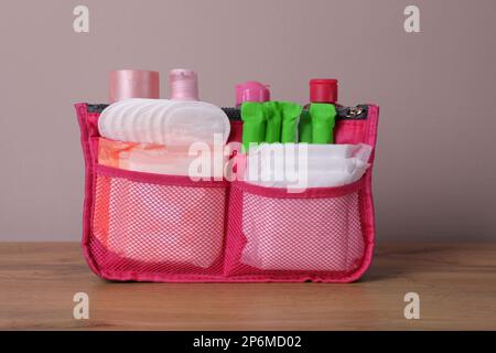 Sac de rangement avec tapis menstruels, tampons et produits de soin de la peau sur une table en bois Banque D'Images