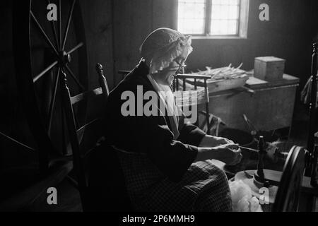 Une actrice en costume colonial travaille à une roue tournante avec de la laine devant une fenêtre pendant une reconstitution de la guerre d'indépendance à l'infirmière Rebecca ho Banque D'Images