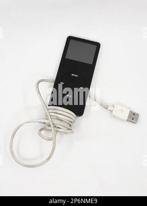 Gros plan sur un lecteur de musique vintage noir mp3 appelé Apple ipod nano avec câble de chargement isolé sur fond blanc Banque D'Images