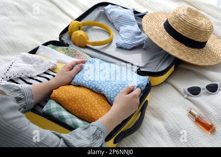 Femme emballant la valise pour le voyage sur le lit, gros plan Banque D'Images