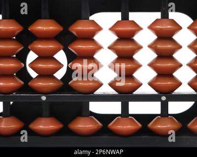 gros plan de perles brunes disposées sur les tiges d'un outil mathématique vintage abacus sur fond blanc Banque D'Images