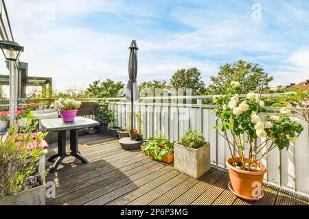 Amsterdam, pays-Bas - 10 avril 2021 : un balcon avec des fleurs en pot sur la table et un parasol dans le ciel est bleu, blanc et rose Banque D'Images