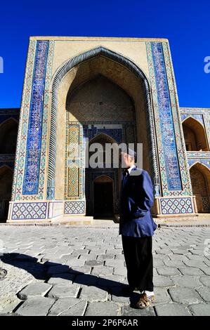 Un ouzbek debout devant la medressa d'Ulugbek à Boukhara, en Ouzbékistan. Banque D'Images