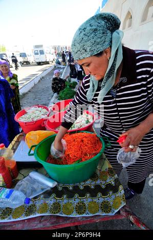 Les femmes ouzbèkes vendent des carottes et des choux hachés sur le marché coloré de Boukhara, en Ouzbékistan. Banque D'Images