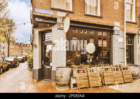 l'extérieur d'un restaurant avec des bancs en bois et des tables en face sur une rue pavée de briques bordée de voitures garées Banque D'Images