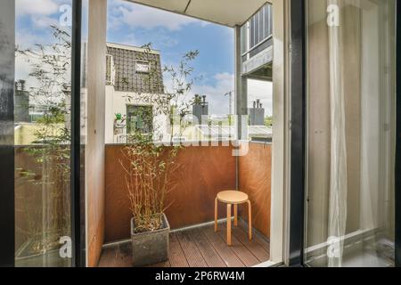 balcon avec chaise et plantes en pot à l'étage, devant une fenêtre ouverte donnant sur l'extérieur Banque D'Images