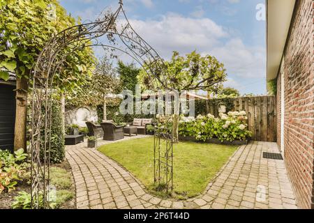 un jardin extérieur avec pavage en briques et chemin de pierre menant à la cour arrière, entouré de plantes vertes luxuriantes Banque D'Images