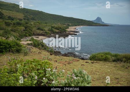 Vue panoramique sur une baie de Flores, entourée d'un paysage verdoyant, au milieu de la mer et en arrière-plan une petite montagne. Banque D'Images