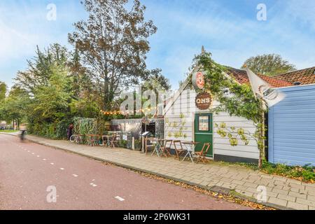 Amsterdam, pays-Bas - 10 avril 2021 : un espace extérieur avec des tables, des chaises et des parasols sur le trottoir devant un bâtiment bleu qui a été peint en blanc Banque D'Images