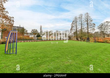 Amsterdam, pays-Bas - 10 avril, 2021: Un parc avec quelques balançoires et d'autres choses sur l'herbe dans la photo est prise de derrière, c'est ciel bleu Banque D'Images