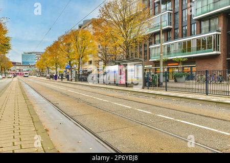 Amsterdam, pays-Bas - 10 avril 2021 : rue de la ville avec des personnes marchant sur les trottoirs et les bâtiments en arrière-plan, prise d'un train en mouvement Banque D'Images