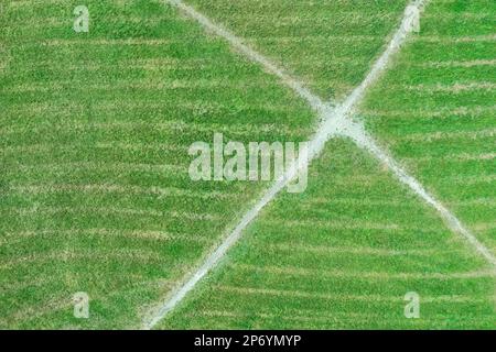 arrière-plan rayé de texture d'herbe verte avec intersection de chemins de marche. vue de dessus de l'antenne. Banque D'Images