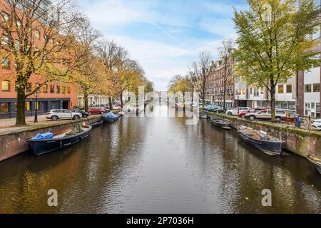 quelques bateaux dans l'eau et des bâtiments des deux côtés, avec des arbres bordant le côté du canal à droite Banque D'Images