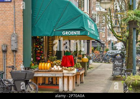 un porte-fruits sur le côté d'une rue avec des vélos garés devant lui et un parasol sur la table Banque D'Images