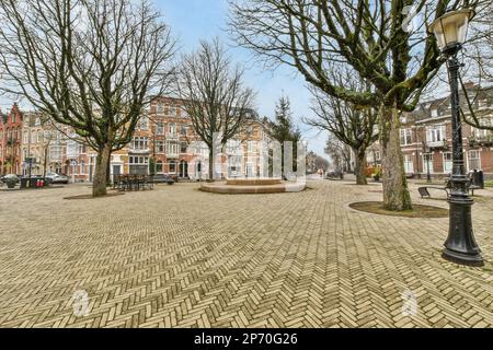 Amsterdam, pays-Bas - 10 avril 2021 : une rue vide au milieu d'une petite ville avec des arbres et des bâtiments des deux côtés, tous alignés Banque D'Images