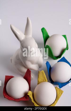 photo de lapin blanc et carton d'œufs multicolore sur fond blanc Banque D'Images