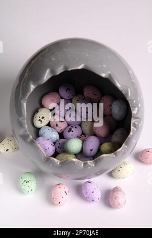 photo dans un gros œuf gris, il y a de petits œufs multicolores sur fond blanc Banque D'Images
