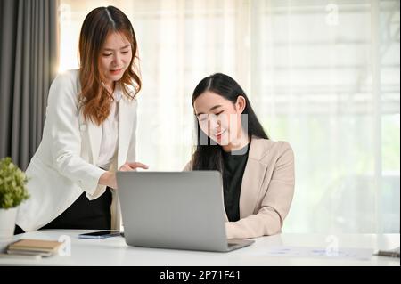 Deux femmes d'affaires ou collègues de bureau asiatiques du millénaire sont en train de brainstorming et de planifier un projet ensemble au bureau. Banque D'Images