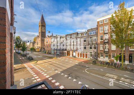 Amsterdam, pays-Bas - 10 avril 2021 : une rue avec des bâtiments en arrière-plan et une tour d'horloge de l'autre côté de la rue, vue depuis une fenêtre ouverte Banque D'Images