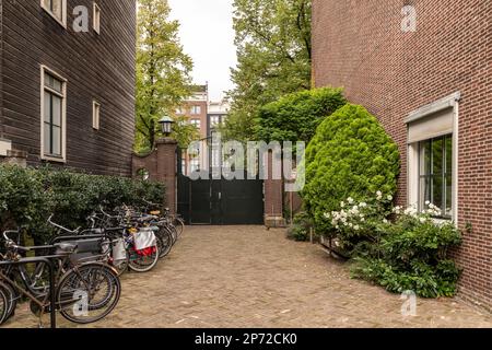 deux vélos garés sur le côté d'une rue de la rue en face d'un bâtiment en brique rouge avec des fleurs blanches Banque D'Images