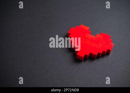 Coeur rouge en briques de plastique sur fond gris foncé Banque D'Images