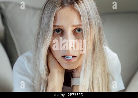 Jeune femme blanche malheureuse avec cheveux blonds mangeant la pilule pour la santé mentale. Fille pensant à de mauvais problèmes de relations, casser avec le petit ami Banque D'Images