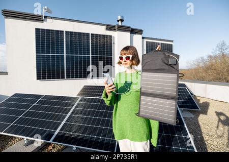 Femme en charge depuis un panneau solaire portable Banque D'Images