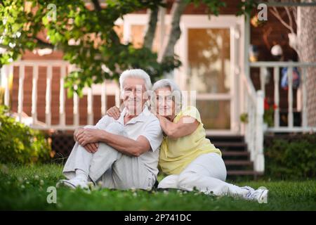 Couple âgé assis sur l'herbe en été Banque D'Images