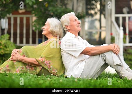 Couple âgé assis sur l'herbe en été Banque D'Images