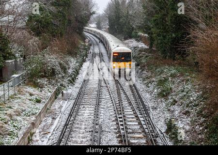 LONDRES, Royaume-Uni - 8th MARS 2023 : train sur les chemins de fer de Londres pendant une journée d'hiver enneigée. Banque D'Images