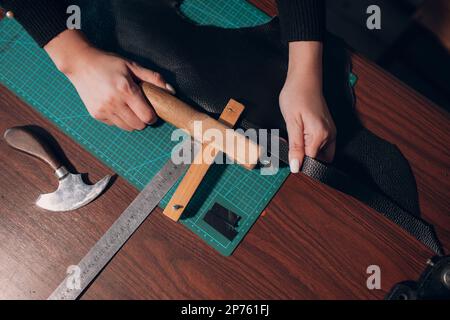 Tanner femme coupant des articles en cuir sur l'atelier.Processus de travail de l'artisan du cuir. Banque D'Images